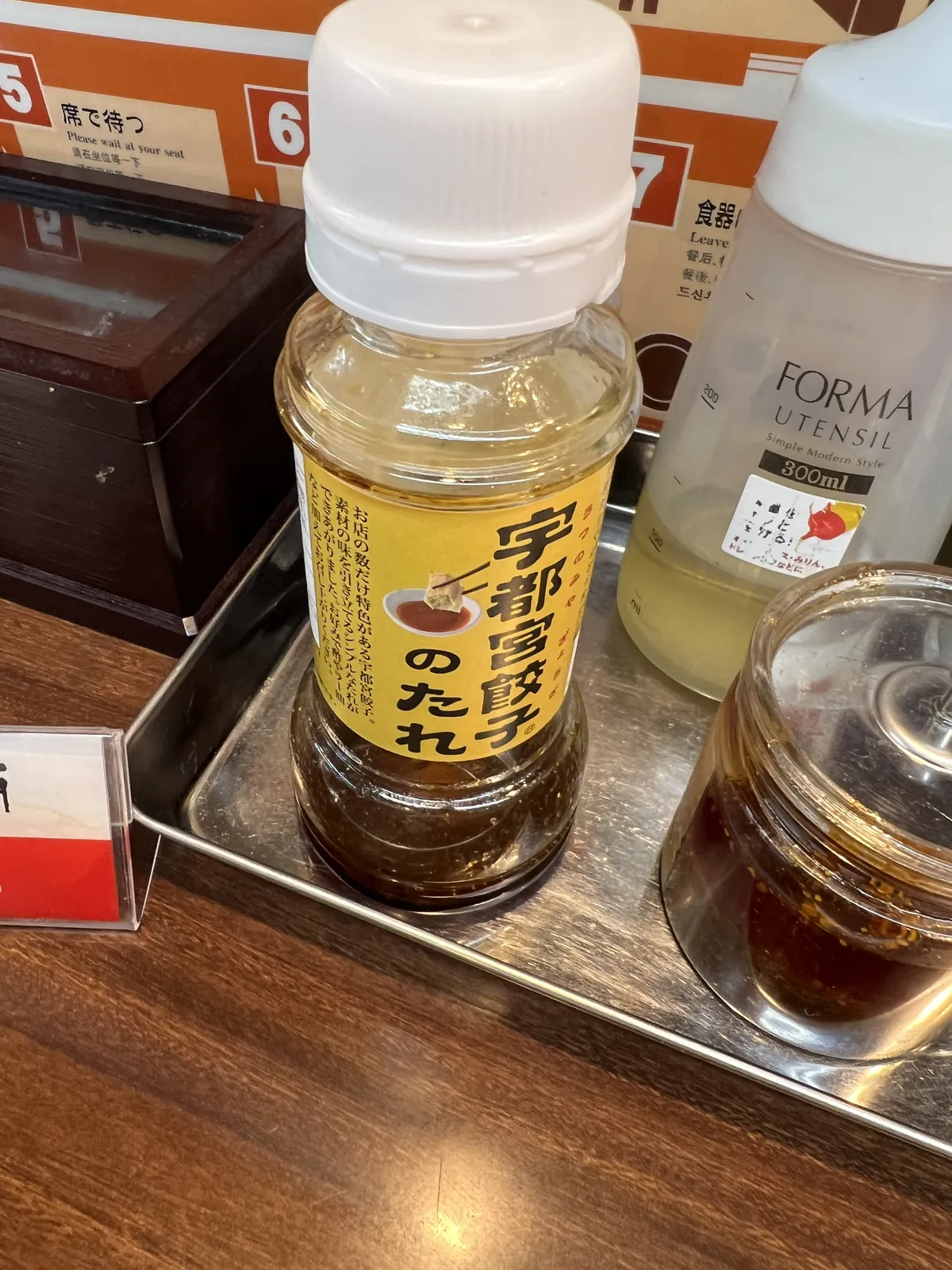 卓上の「宇都宮餃子のたれ」のボトルと、酢・ラー油の容器。