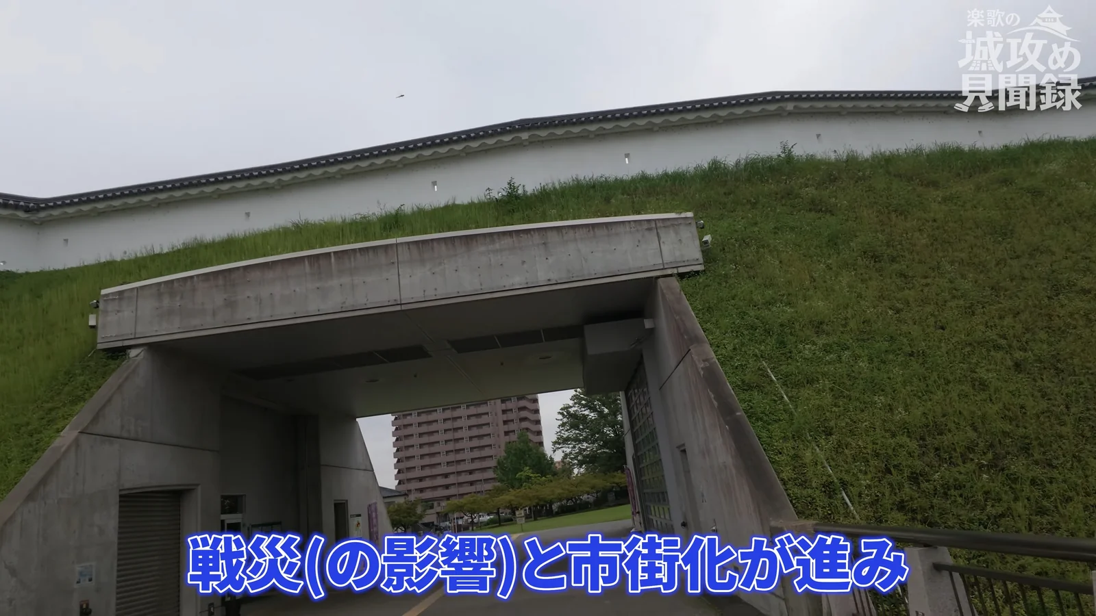 宇都宮城址公園の土塁。芝に覆われた土手の上に白壁が続き、下をくぐる通路が開いている。